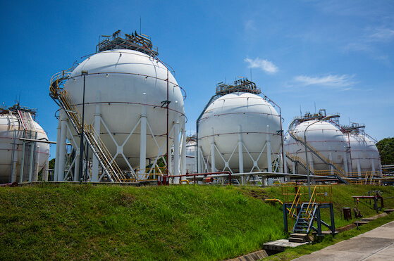 White spherical propane tanks containing fuel gas pipeline on a field. Used to generate energy.